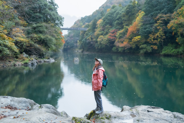 ポツポツ雨を見上げるピンクのジャケットを来た登山者