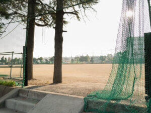 誰もいない高校のグラウンドに午後の光が射しているところ