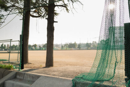 誰もいない高校のグラウンドに午後の光が射しているところ